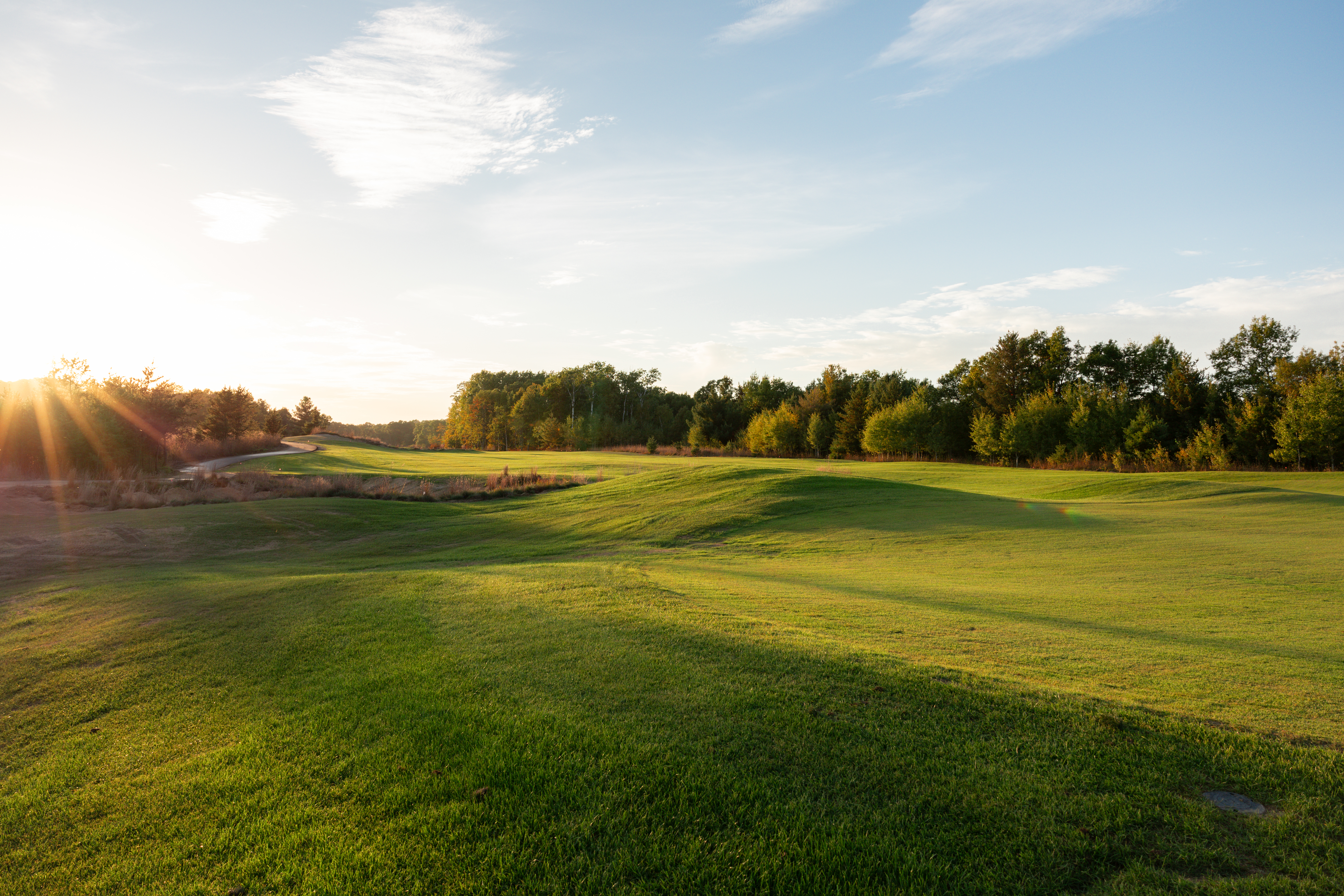 A stunning sunset over the 2nd green at The Farm Golf Links, highlighting the rolling fescue-covered dunes and links-style bunkers of the newest 9-hole course at Crosswoods.